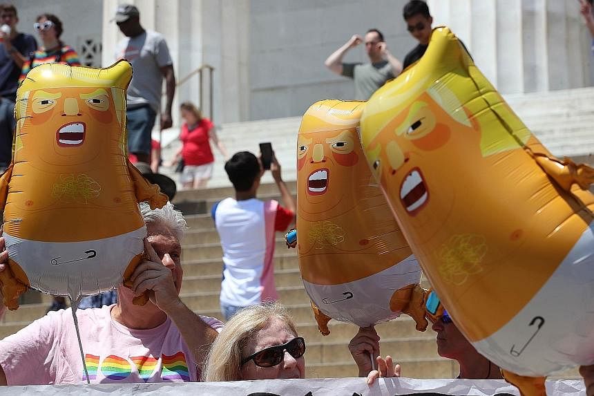Top: People marching in the Independence Day parade in Washington DC. Above: Members of activist group Code Pink with "Baby Trump" balloons depicting the President in diapers. AGENCE FRANCE-PRESSE People posing in front of a Bradley fighting vehicle 