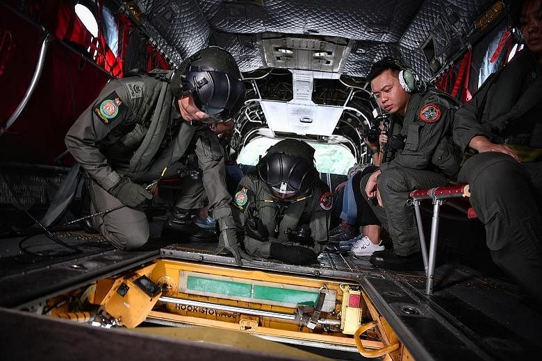 First Warrant Officer Vijaikumar Rangabashayam lying prone on the helicopter floor near a hatch above the flag where he can see how it unfolds.