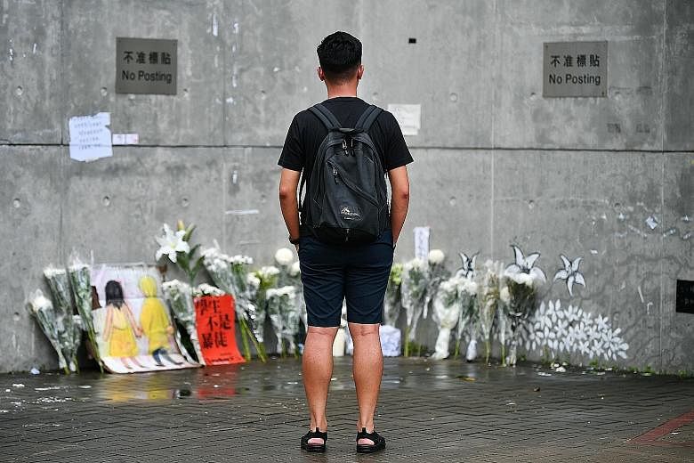 Events organiser Adrian Lam standing at the memorial at Lennon Wall near the Central Government Complex in Admiralty, Hong Kong. Protest artwork and post-it notes have been torn down and all that remains are bouquets to commemorate the three people w