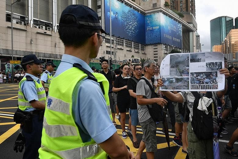 Above: A woman confronting a police officer with a poster critical of the police's handling of protesters. ST PHOTO: CHONG JUN LIANG Right: Police officers arresting a protester after a separate group of marchers took to the streets in Mongkok last n