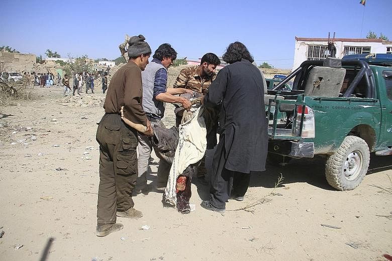 Afghans moving an injured man from the scene after Taleban fighters detonated a car bomb in Ghazni. The Taleban have continued attacks despite increased US efforts towards a peace deal to end the 18-year war.