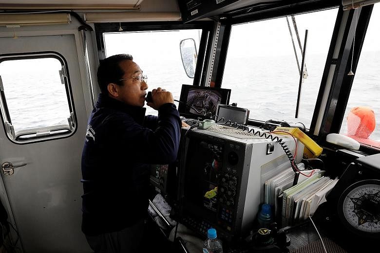 Whale-watching boat captain Masato Hasegawa (above) sounding the alert that killer whales (right) are spotted in the sea near Rausu in Hokkaido. PHOTOS: REUTERS