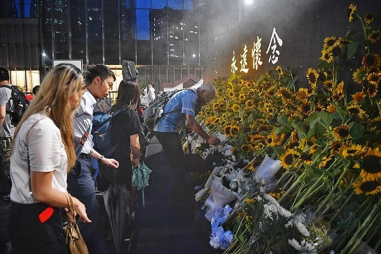 People laying sunflowers at a memorial service on Thursday night for a protester who died after falling from a scaffolding.