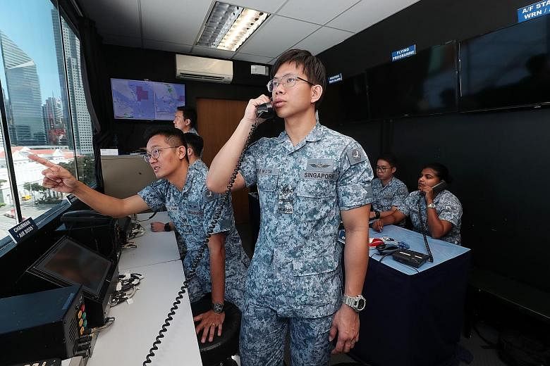 Military Expert 2 Tai Wei Jing (standing) and ME2 Pang Teck Lim (beside him), who are responsible for communications for the Air Participation Committee, at the control room at the National Gallery Singapore yesterday.