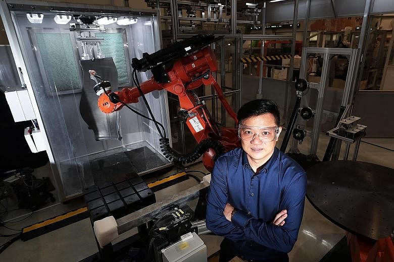 Mr Desmond Nyo, manager at KA Industrial Engineering, with a robot that automates spraying protective coatings on fan blades of aircraft engines. ST PHOTO: KELVIN CHNG