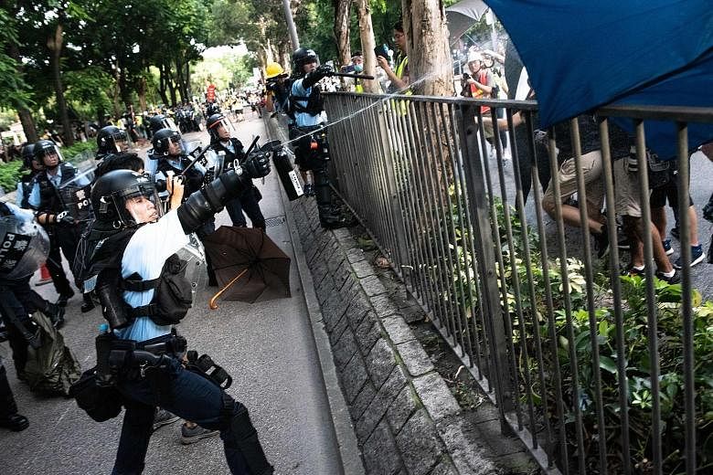 Left: A protester hanging on for his life as bystanders managed to hold on to him before policemen pulled him to safety. He had jumped over the barrier, not realising that he was on an overhead bridge. ST PHOTO: CHONG JUN LIANG