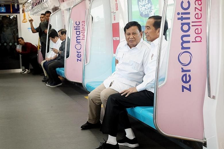 President Joko Widodo (right) with retired army general and defeated presidential candidate Prabowo Subianto during their 18-minute ride on the country's first MRT line in Jakarta yesterday.