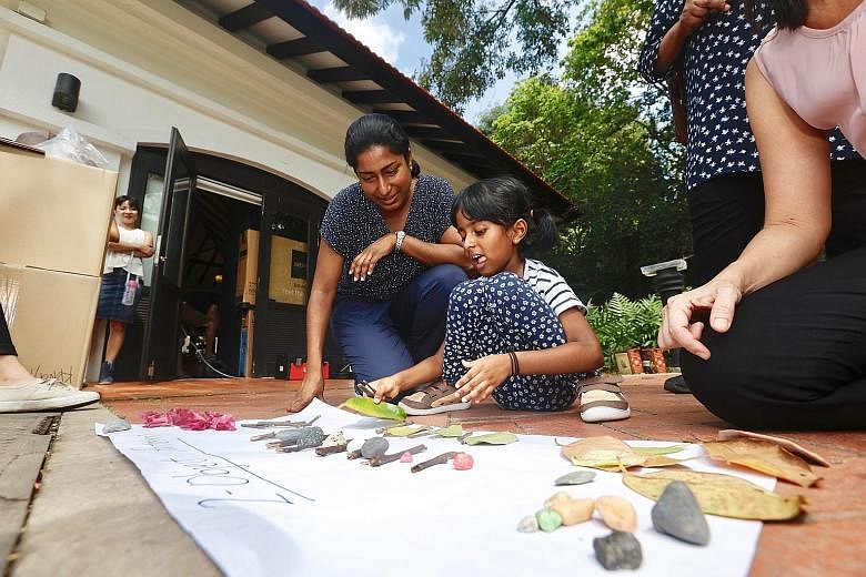Mrs Shamala Ganessaraj watching as her six-year-old daughter Aarya formed patterns with pebbles, leaves and twigs - items collected from outdoors - at Fort Canning Park yesterday.