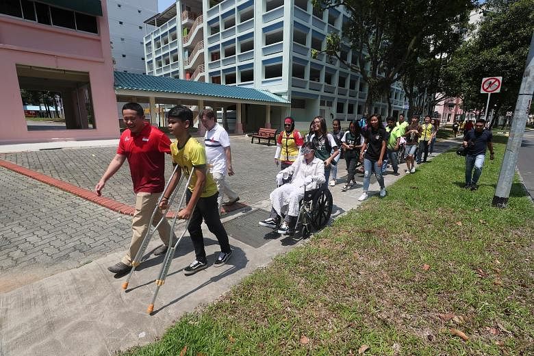Above: Woodlands Youth League football players trying to put on clothes while wearing gloves and blurred vision goggles, to simulate the challenges the elderly face. Right: Football players on wheelchairs and crutches making their way along a 400m ro