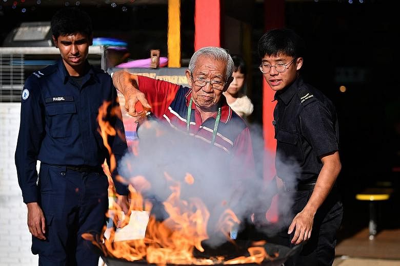 Above: Retiree Tan Boon Tien, 84, being taught how to use a fire extinguisher by members of the Singapore Civil Defence Force at a community event at West Coast Market Square yesterday. Right: West Coast GRC MP S. Iswaran watching people learn how to