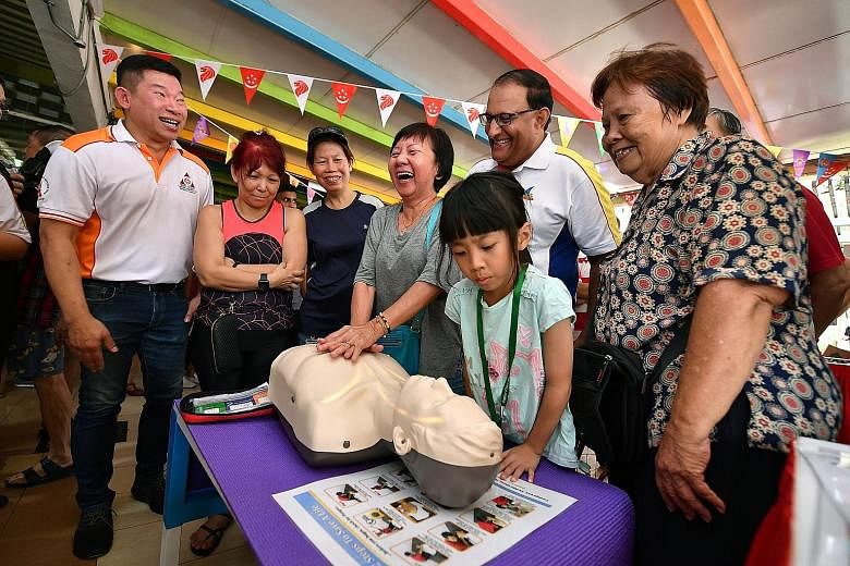 Above: Retiree Tan Boon Tien, 84, being taught how to use a fire extinguisher by members of the Singapore Civil Defence Force at a community event at West Coast Market Square yesterday. Right: West Coast GRC MP S. Iswaran watching people learn how to