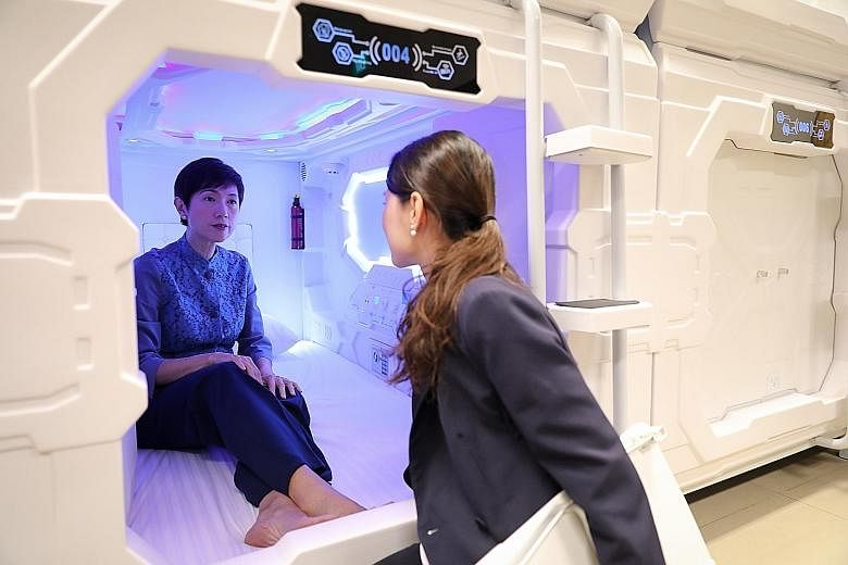 Manpower Minister Josephine Teo yesterday trying out a capsule bed for staff of Grand Park City Hall hotel as Ms Lim Jiahui, the hotel's marketing and communications manager, looked on. ST PHOTO: ONG WEE JIN