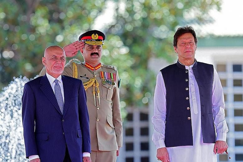 Visiting Afghan President Ashraf Ghani (left) and Pakistani Prime Minister Imran Khan (right) reviewing an honour guard during a welcome ceremony in Islamabad last month. PHOTO: AGENCE FRANCE-PRESSE