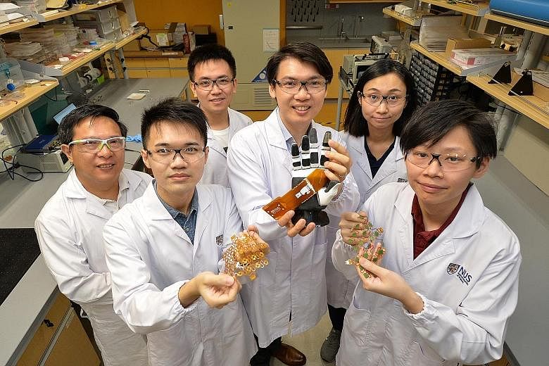 Assistant Professor Benjamin Tee with a robotic hand that has electronic skin attached to the index finger. With him are (from left) research fellow Ng Kian Ann; PhD students Li Si and Yao Haicheng; and research fellows Tan Yu Jun and See Hian Hian. 