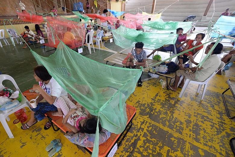 Patients with dengue fever resting under mosquito nets in a gym in Maasin, a town in the Philippine province of Iloilo, yesterday. On Monday, the Philippine Department of Health issued a national alert to warn of an outbreak of dengue fever, with mor
