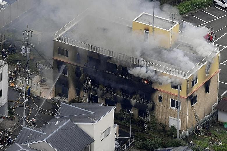 Firefighters battling the blaze yesterday at the three-storey Kyoto Animation building in western Japan. A man who poured what appeared to be petrol around the building has been held. PHOTO: REUTERS