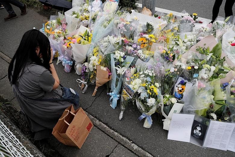 A woman praying at the site of the torched Kyoto Animation building in Kyoto yesterday. Fifteen of the 34 victims of Thursday's arson attack were in their 20s and 11 in their 30s, some joining the company only in April.