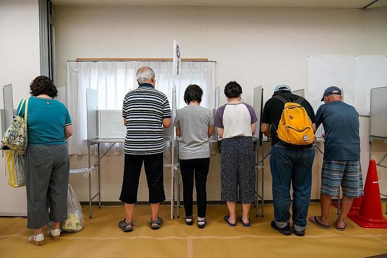 Voters filling in ballot papers at a polling station in Yokohama during Japan's Upper House election yesterday.