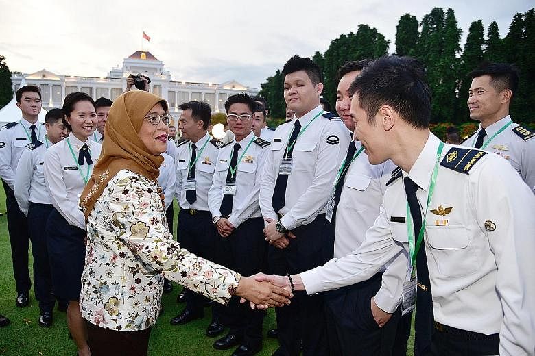 President Halimah Yacob greeting Military Expert 1 Alvin Yoong during a reception yesterday at the Istana for about 500 personnel from the Ministry of Defence (Mindef) and the Singapore Armed Forces (SAF). Among the guests were Defence Minister Ng En