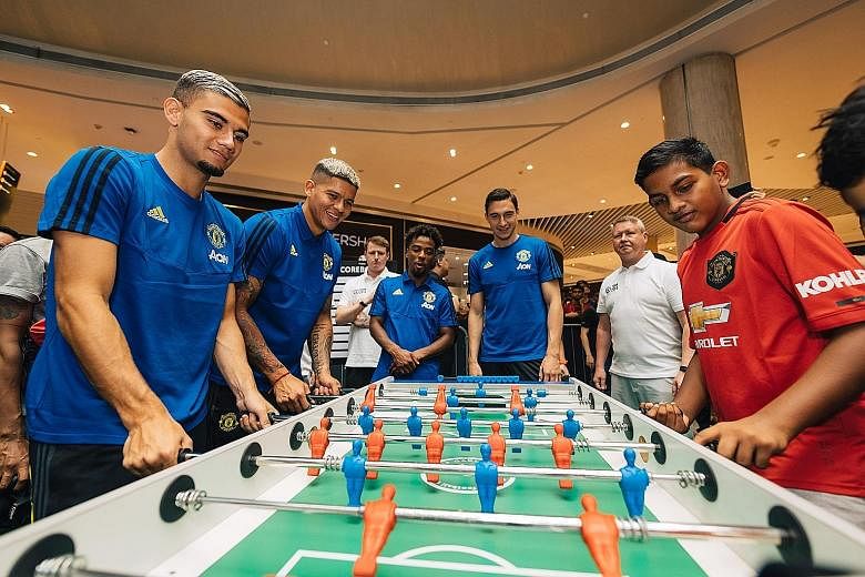 United players (from left) Andreas Pereira, Marcos Rojo, Angel Gomes and Matteo Darmian playing table football with fans at The Maybank Manchester United Tour 2019 held at Suntec City.