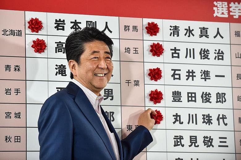 Japanese Premier Shinzo Abe highlighting the names of winning candidates with paper flowers at the Liberal Democratic Party's headquarters in Tokyo yesterday.