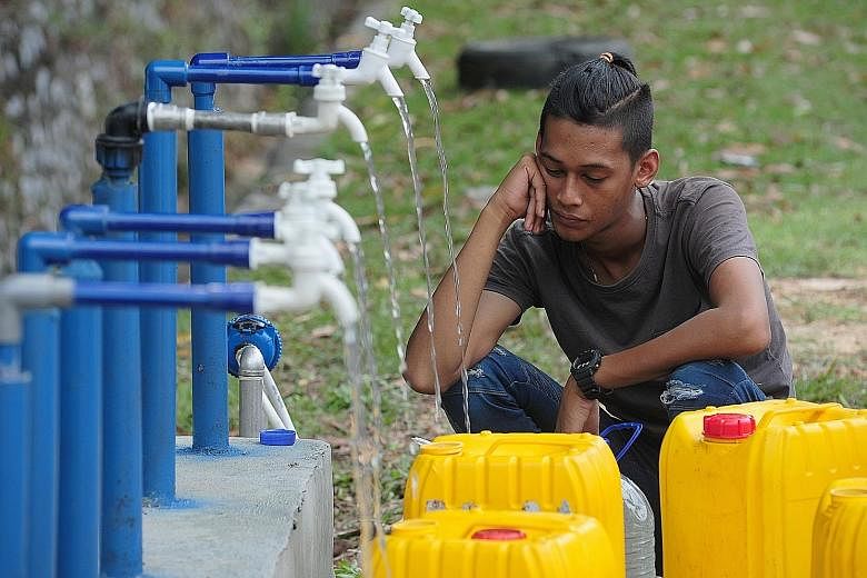 A man filling up his containers with water from pipes yesterday, after supply was cut off in Selangor. Millions of consumers like him were affected by the second water outage in days. PHOTO: BERNAMA