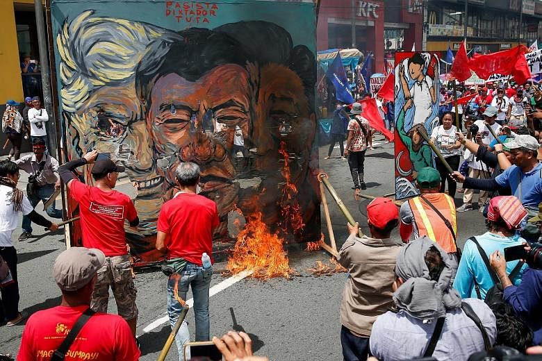 Philippine activists burning a poster of presidents Donald Trump of the US, Rodrigo Duterte of the Philippines and Xi Jinping of China during a protest in Quezon City yesterday, amid demonstrations by Mr Duterte's critics and supporters as he was del