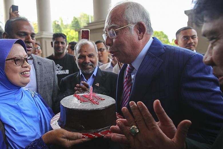 Former Malaysian prime minister Najib Razak blowing out the candle as he celebrated his 66th birthday with his supporters in the lobby of a court complex at the Kuala Lumpur High Court yesterday. Najib is facing several criminal proceedings over the 