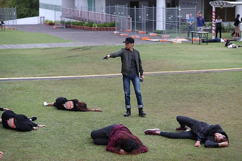 An "injured" student being stretchered off by personnel from the Singapore Civil Defence Force yesterday. A "gunman" taking down students who were attending a campus concert, during an emergency preparedness exercise at Republic Polytechnic yesterday