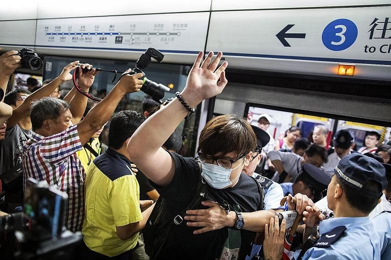 A police officer removing a demonstrator who was preventing the doors of a train from closing at Admiralty station in Hong Kong yesterday. The disruption by a small group of protesters caused travel delays during the morning rush hour.