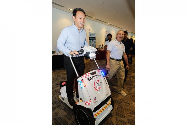 Minister of State for Manpower and National Development Zaqy Mohamad (left) trying out the Tatanka buggy, an electric three-wheeled vehicle that can be used for patrols, at yesterday's event.