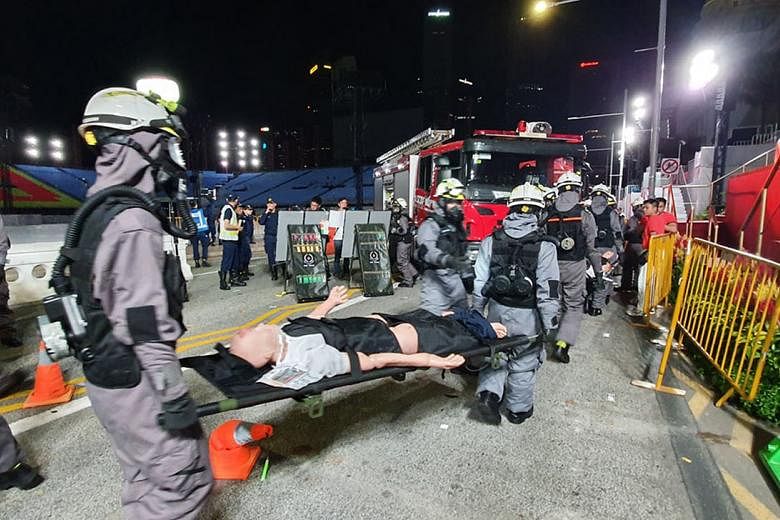 SCDF officers in protective suits moving "casualties" to the decontamination point at the Padang during the exercise early yesterday morning.