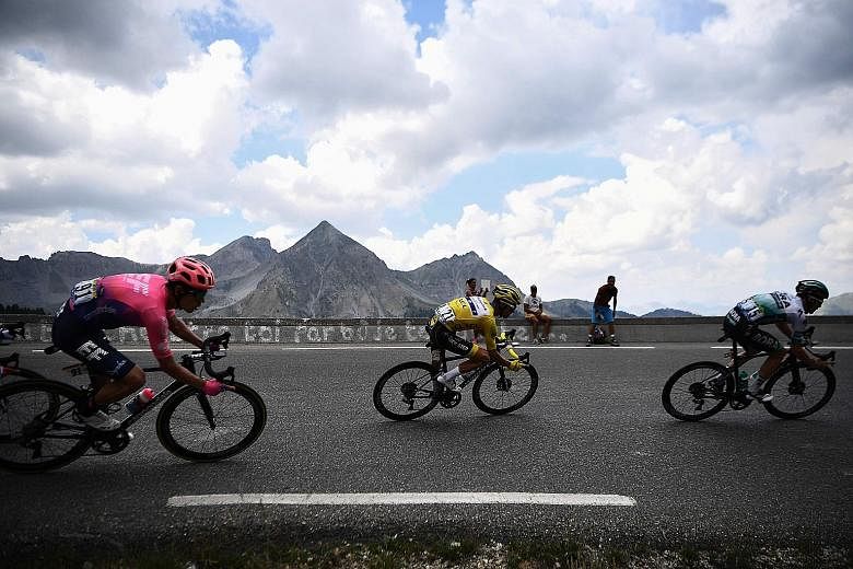 Julian Alaphilippe, in the yellow jersey, is sandwiched between Rigoberto Uran (left) and Gregor Muhlberger on a curve during the 18th stage of the Tour yesterday. PHOTO: AGENCE FRANCE-PRESSE