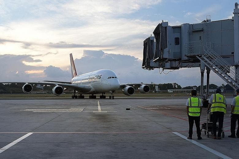 SIA Engineering technicians standing by as a plane pulls into Changi Airport. The company says it has begun to note improvement in manpower utilisation, productivity and turnaround time from its transformation initiatives and adoption of technologies