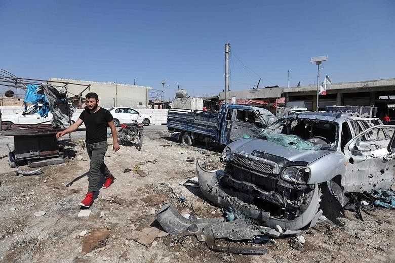 A Syrian walking past damaged cars following an air strike on a market in the town of Saraqib in Syria's north-western province of Idlib yesterday. PHOTO: AGENCE FRANCE-PRESSE