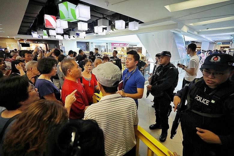 Police had to be called in to manage the situation at several Huawei stores across the island yesterday, including at Nex mall (right) in Serangoon. Things got heated when customers, who had queued for hours for Huawei's $54 smartphone promotion, wer
