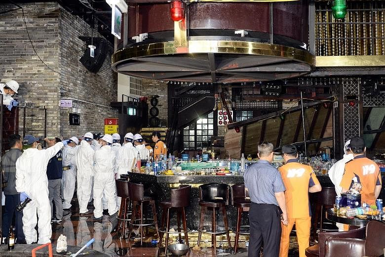 South Korean firefighters and officials examining the collapsed balcony inside a nightclub in Gwangju, South Korea, yesterday. Several athletes competing at the swimming world championships were injured in the accident.