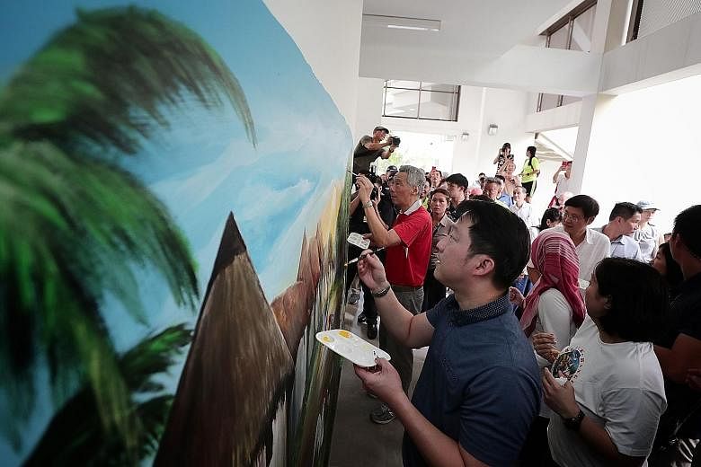 Prime Minister Lee Hsien Loong and Dr Lam Pin Min, MP for Sengkang West and adviser to the SMC's grassroots organisations, adding the finishing touches to a wall mural depicting life in the past by artist Vincent Seet yesterday. Mr Seet and fellow Ja