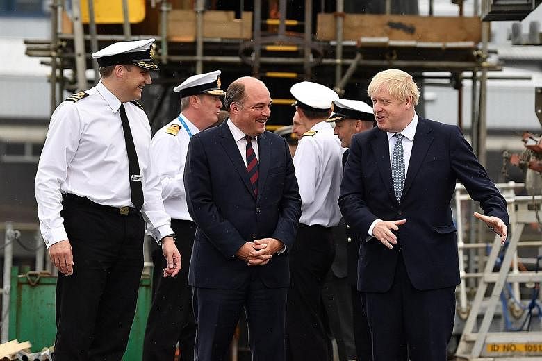From left: Commander Justin Codd with Britain's Defence Secretary Ben Wallace and Prime Minister Boris Johnson aboard the submarine, HMS Victorious, during a visit to Scotland on Monday.