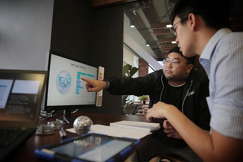 Reporter Lester Wong (left) learning to operate the Sphero robot under the watchful eye of instructor Melvin Lin (far left), a manager in IMDA's digital literacy and participation division.