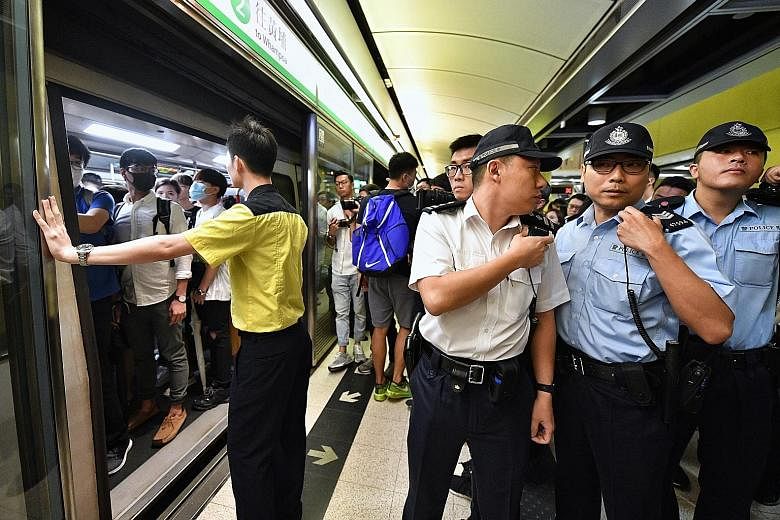Police officers at Tiu Keng Leng Station during the disruption of train services yesterday. Tempers flared at the various affected stations and the police were called, but no arrests were made. An angry passenger (centre) who elbowed a protester out 