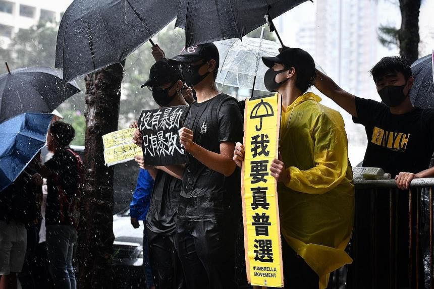 People braving the rain outside the Eastern Magistrates' Court in Hong Kong to show support for those charged yesterday. Hong Kong has been hit by eight straight weeks of mass protests sparked by the now-suspended extradition Bill. A man trying to sh