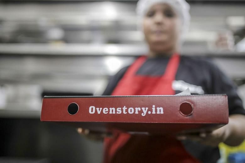 Employees preparing orders (left) at a Rebel Foods cloud kitchen in the Indian city of Mumbai. The company serves a dozen different menus with everything from cheese-loaded Italian pizzas (above) to 99 variations of the dosa, a lentil-and-rice crepe.