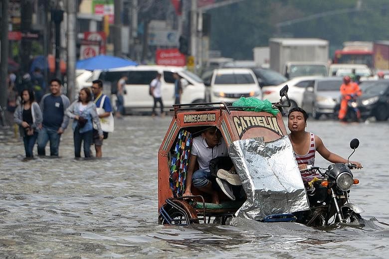 Residents riding through a flooded street in Manila yesterday following heavy rain brought about by a south-west monsoon. PHOTO: AGENCE FRANCE-PRESSE