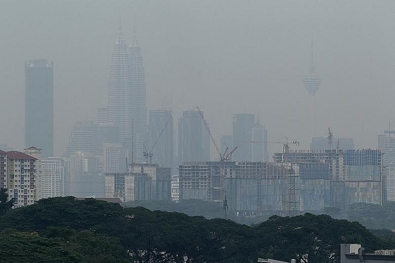 The Petronas Twin Towers and KL Tower in Kuala Lumpur shrouded in haze on Thursday morning as a result of fires in Indonesia's Riau province. PHOTO: BERNAMA Firefighters battling a wildfire in Indonesia's Riau province on Thursday. The fires have led