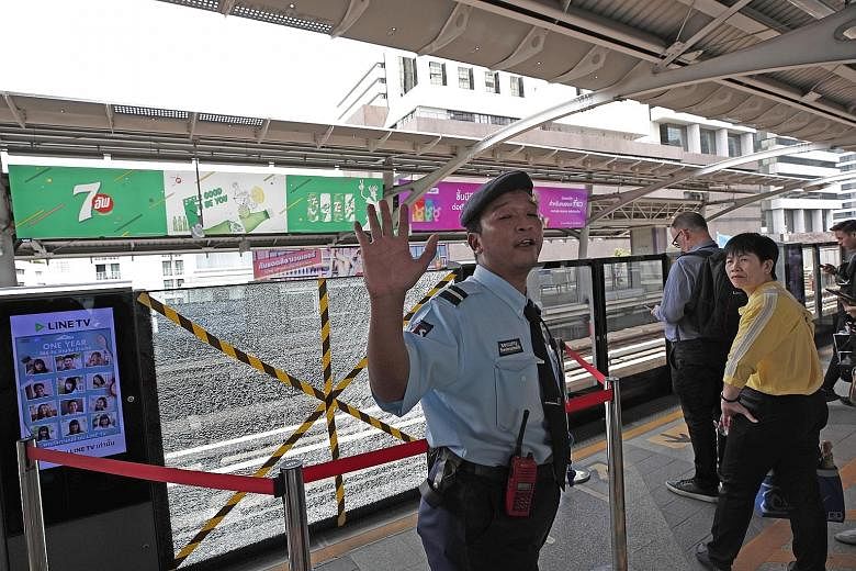 A security officer guarding a shattered platform door at the Bangkok skytrain station near where a small bomb exploded yesterday morning during rush hour, sending commuters fleeing. PHOTO: EPA-EFE