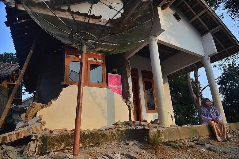 A survivor outside a house in Pandeglang that was damaged by the 6.9-magnitude earthquake that rocked Indonesia's Java island on Friday night. The quake killed at least five people and injured four others. PHOTOS: AGENCE FRANCE-PRESSE
