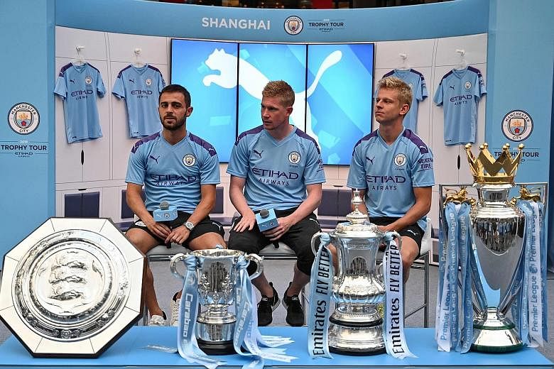 Manchester City players (from far left) Bernardo Silva, Kevin de Bruyne and Oleksandr Zinchenko with the club's four trophies won last season - Community Shield, League Cup, FA Cup and English Premier League. They were at a promotional event in Shanghai o