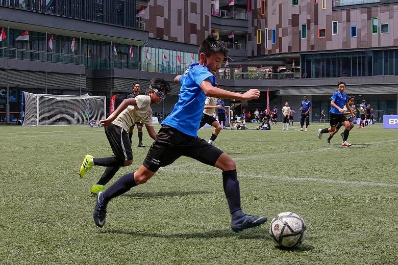ActiveSG Football Academy Serangoon Development Centre's Under-13 side (in blue) taking on AFA Toa Payoh DC at Our Tampines Hub yesterday in the Epson Youth Challenge.