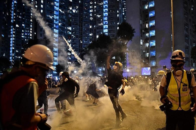 Protesters throwing tear gas canisters back at the police in Wong Tai Sin, in Kowloon, yesterday. Riot police spent most of the day battling anti-extradition protesters who had either surrounded police stations or built barricades on the roads in at 